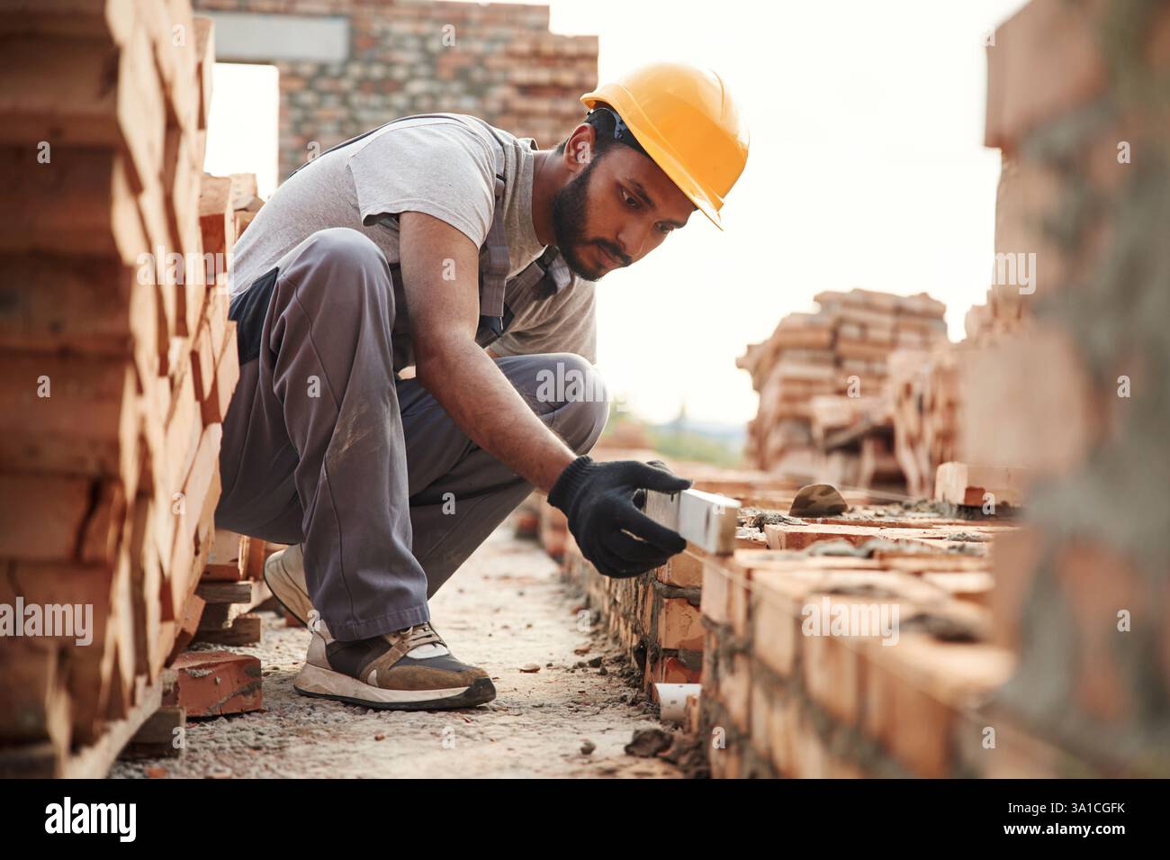 Mit dem Nivellierer. Ein hübscher Indianer ist auf der Baustelle. Stockfoto