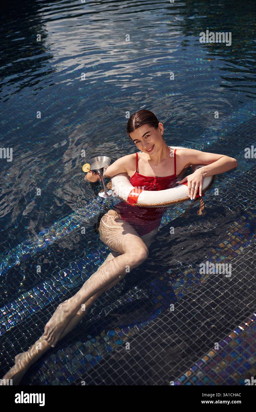 Eine junge Frau in rotem Badeanzug ist im Pool. Stockfoto