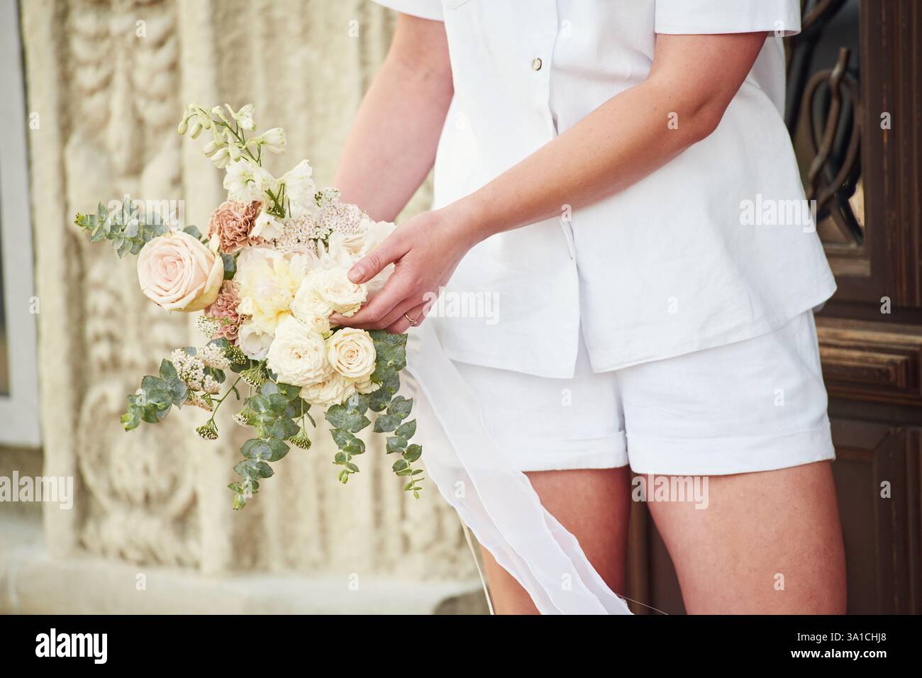 In weißer Kleidung. Nahaufnahme einer Frau mit Blumen in den Händen. Stockfoto