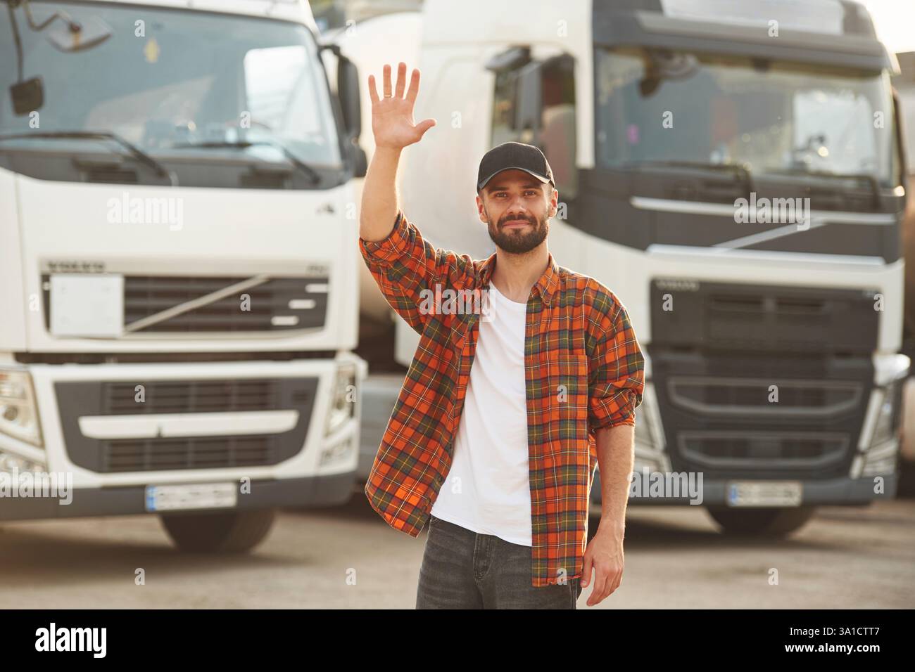 Hallo Geste mit der Hand. Junger Lkw-Fahrer in lässiger Kleidung. Stockfoto