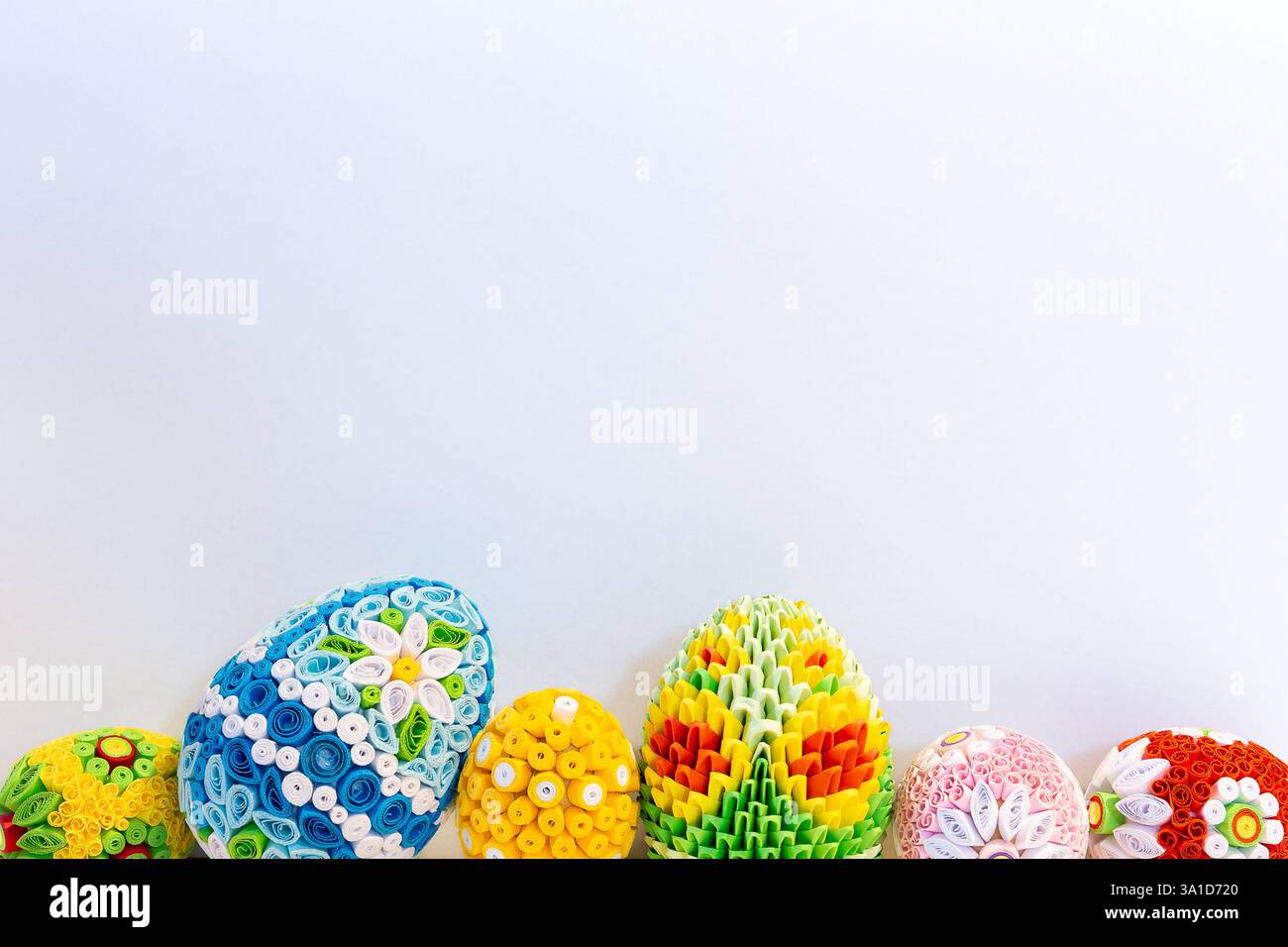 Weißer Osterhintergrund mit bunten Ostereiern mit Blumenschmuck und Origami-Dekorationen unten, Kopierraum. Stockfoto