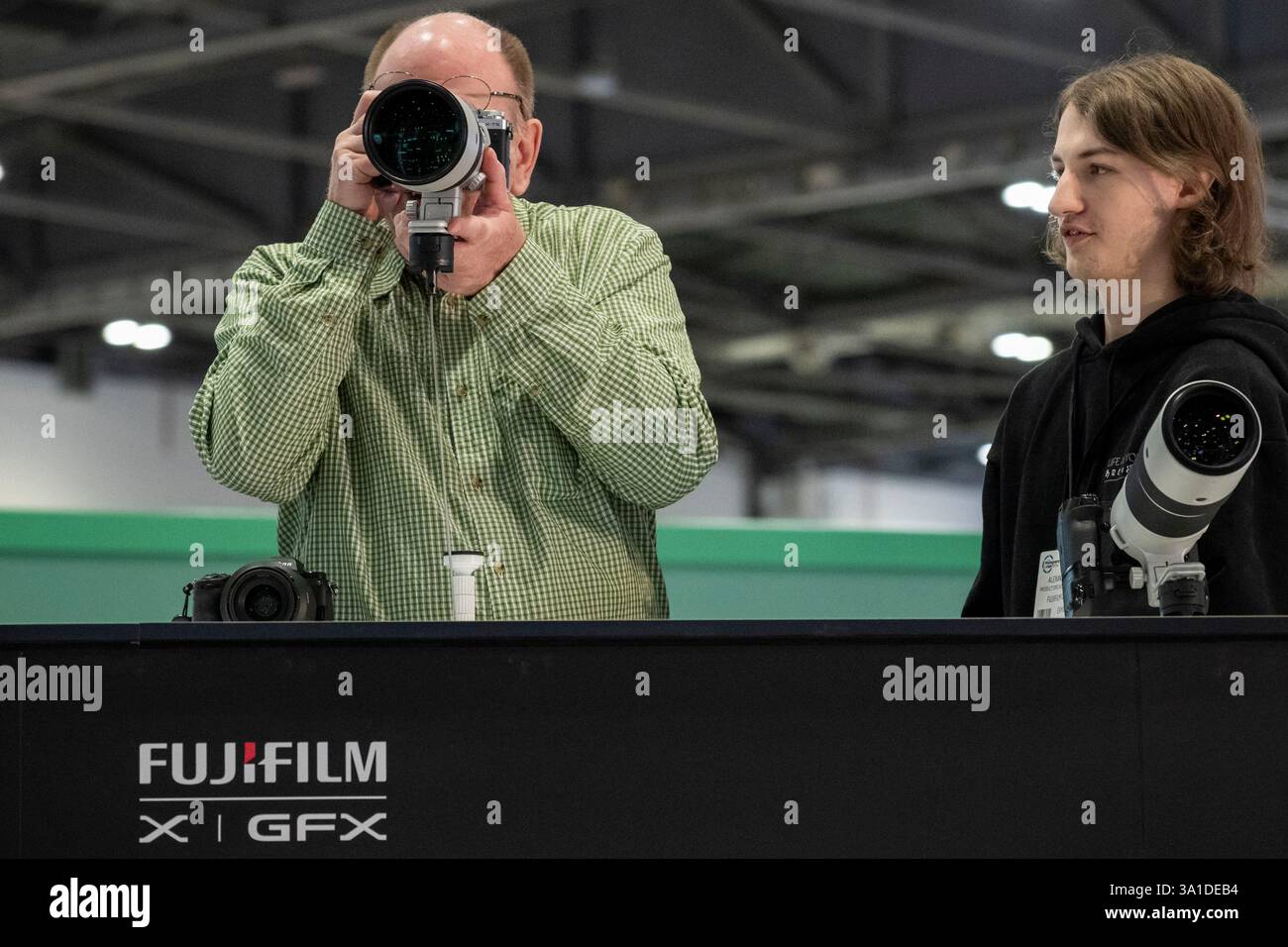 London, Großbritannien. 8. März 2025. Am Eröffnungstag von The Photography & Video im Excel London probieren Besucher lange Objektive auf dem Fuji Stand aus. Die Veranstaltung richtet sich an Profis und Amateure, die die neuesten Techniken erlernen, von Branchenführern und Experten hören und die neueste Technologie und Ausrüstung ausprobieren können. Die Show findet vom 8. Bis 11. März statt. Quelle: Stephen Chung / Alamy Live News Stockfoto