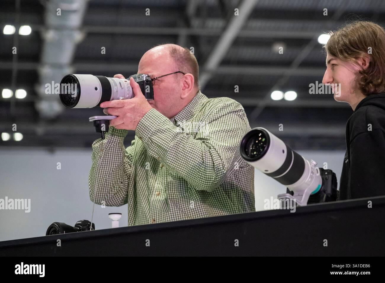 London, Großbritannien. 8. März 2025. Am Eröffnungstag von The Photography & Video im Excel London probieren Besucher lange Objektive auf dem Fuji Stand aus. Die Veranstaltung richtet sich an Profis und Amateure, die die neuesten Techniken erlernen, von Branchenführern und Experten hören und die neueste Technologie und Ausrüstung ausprobieren können. Die Show findet vom 8. Bis 11. März statt. Quelle: Stephen Chung / Alamy Live News Stockfoto
