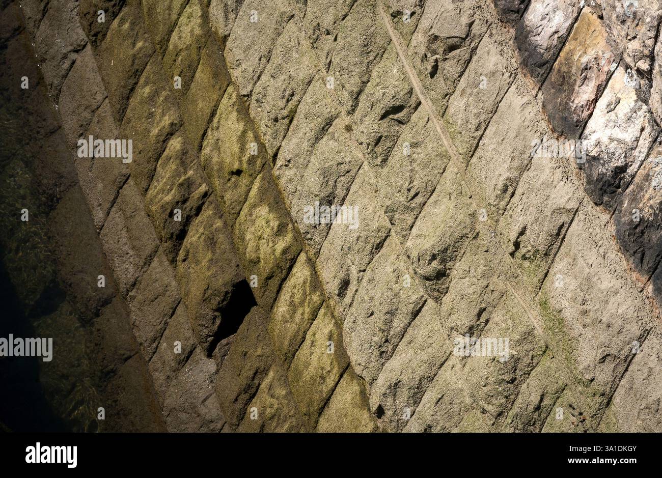 Beton Riverbed Layers – trockene und nasse Strukturen, die die Sonne reflektieren Stockfoto