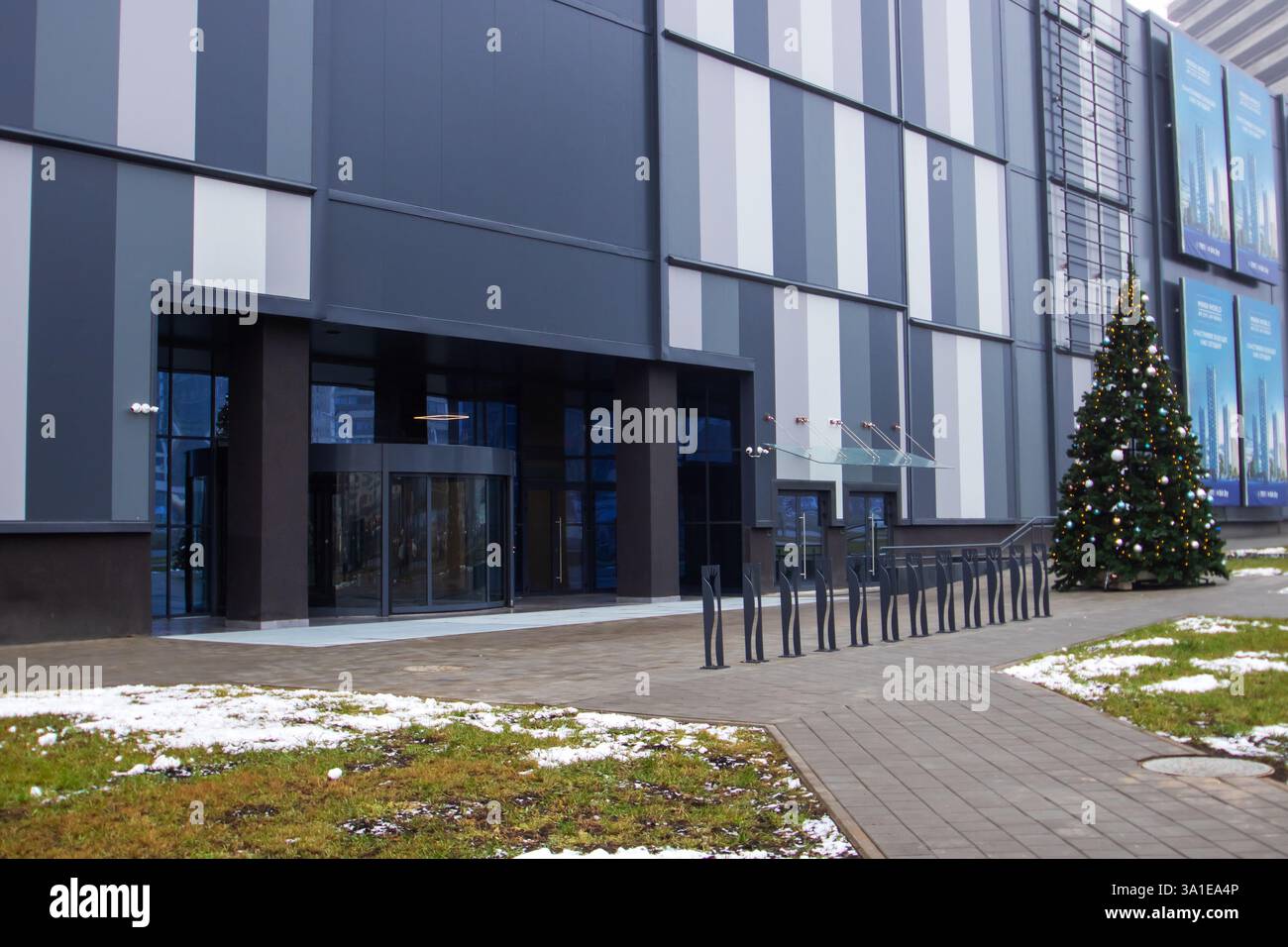 Weißrussland, Minsk - 26, 12, 2024: Vor einem großen Geschäftsgebäude befindet sich ein außergewöhnlich großer und wunderschön geschmückter Weihnachtsbaum Stockfoto