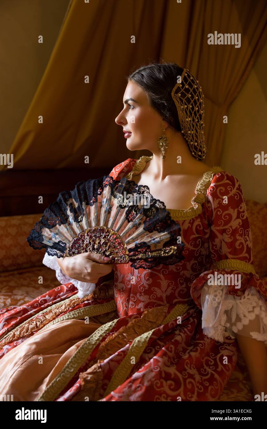 Renaissance-Dame in spätmittelalterlichem Kleid sitzt auf einem schönen Himmelbett in ihrem Schloss Schlafzimmer Stockfoto