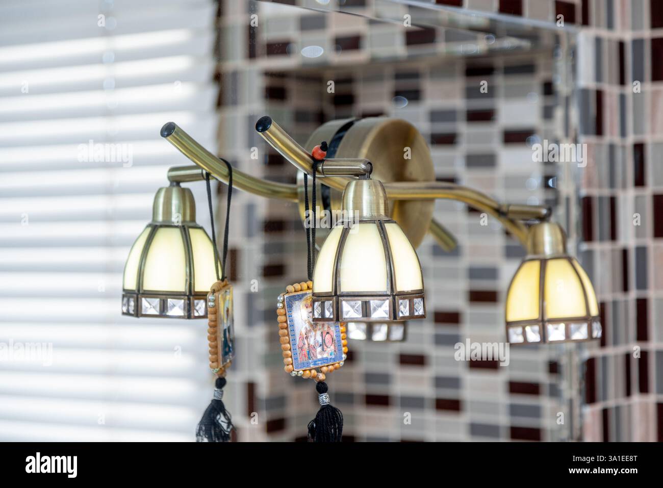 Eine Leuchte mit drei Glühlampen, die an einem Metallstab hängen. Die Glühlampen sind weiß und die Leuchte hängt an einer Wand Stockfoto