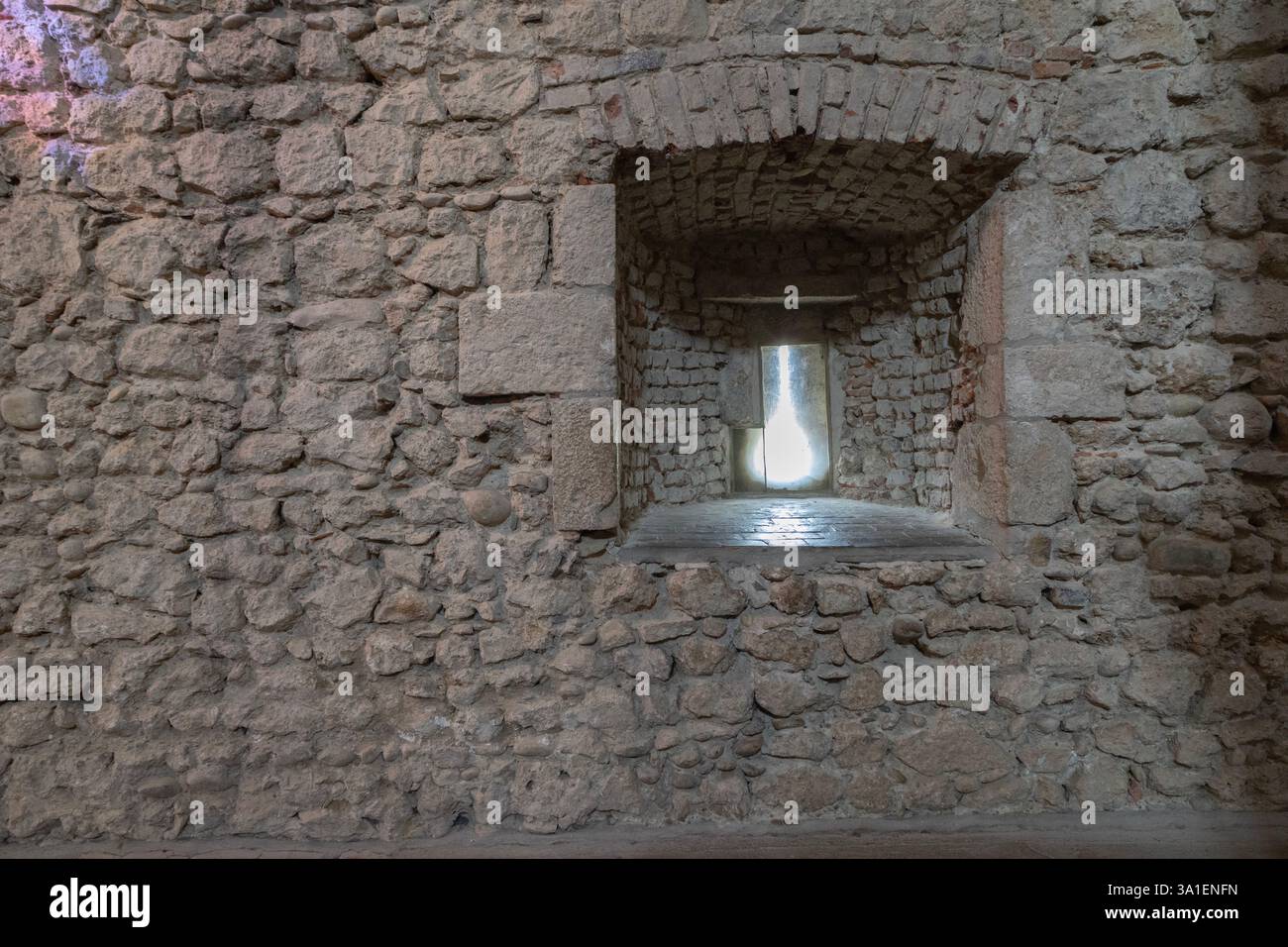 Ein äußerst ungewöhnlicher Pfeilschlitz in der Westmauer der Kirche St. Maria-Magdelene in Pérouges, einem der „schönsten Dörfer Frankreichs“. Stockfoto