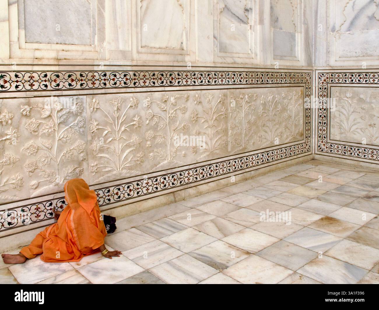 Frau in orangefarbenem Sari mit Marmorrelief und Pietra Dura-Grenze im Taj Mahal, Agra, Indien. Stockfoto