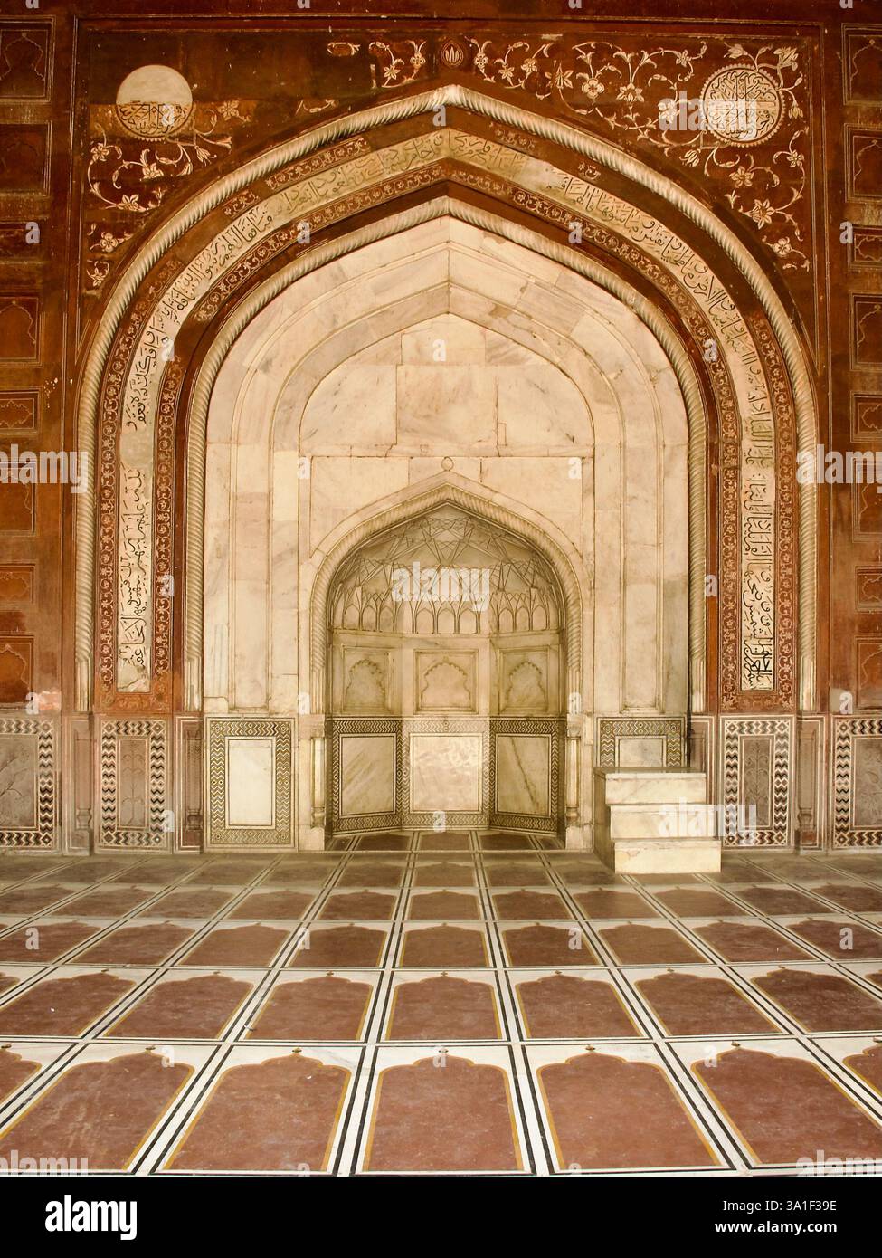 Minbar aus weißem Marmor, eingerahmt von einem roten Sandsteinbogen mit floralen und koranischen Inschriften in der Moschee des Taj Mahal Komplexes in Agra. Stockfoto
