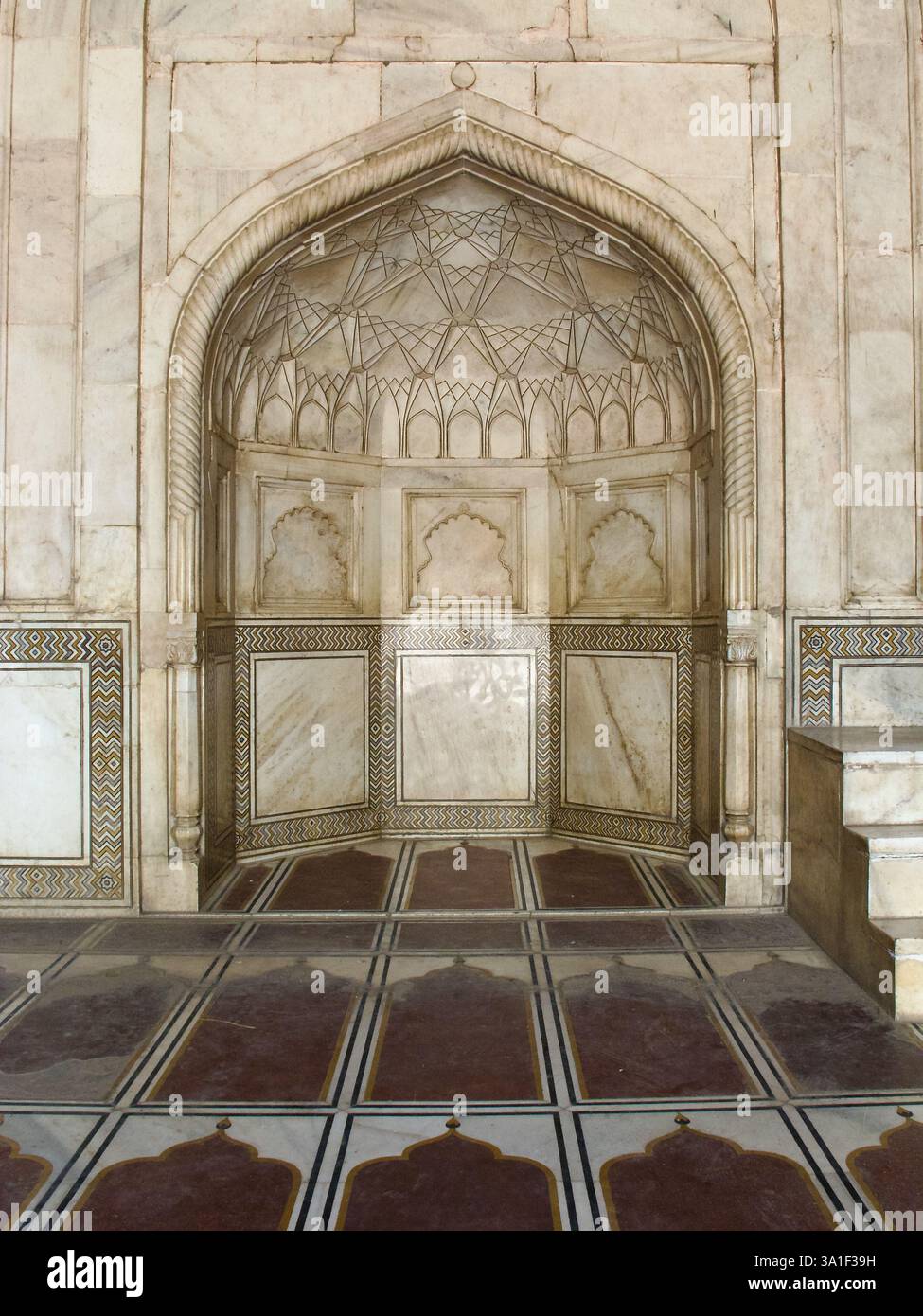 Minbar aus weißem Marmor, eingerahmt von einem roten Sandsteinbogen mit floralen und koranischen Inschriften in der Moschee des Taj Mahal Komplexes in Agra. Stockfoto