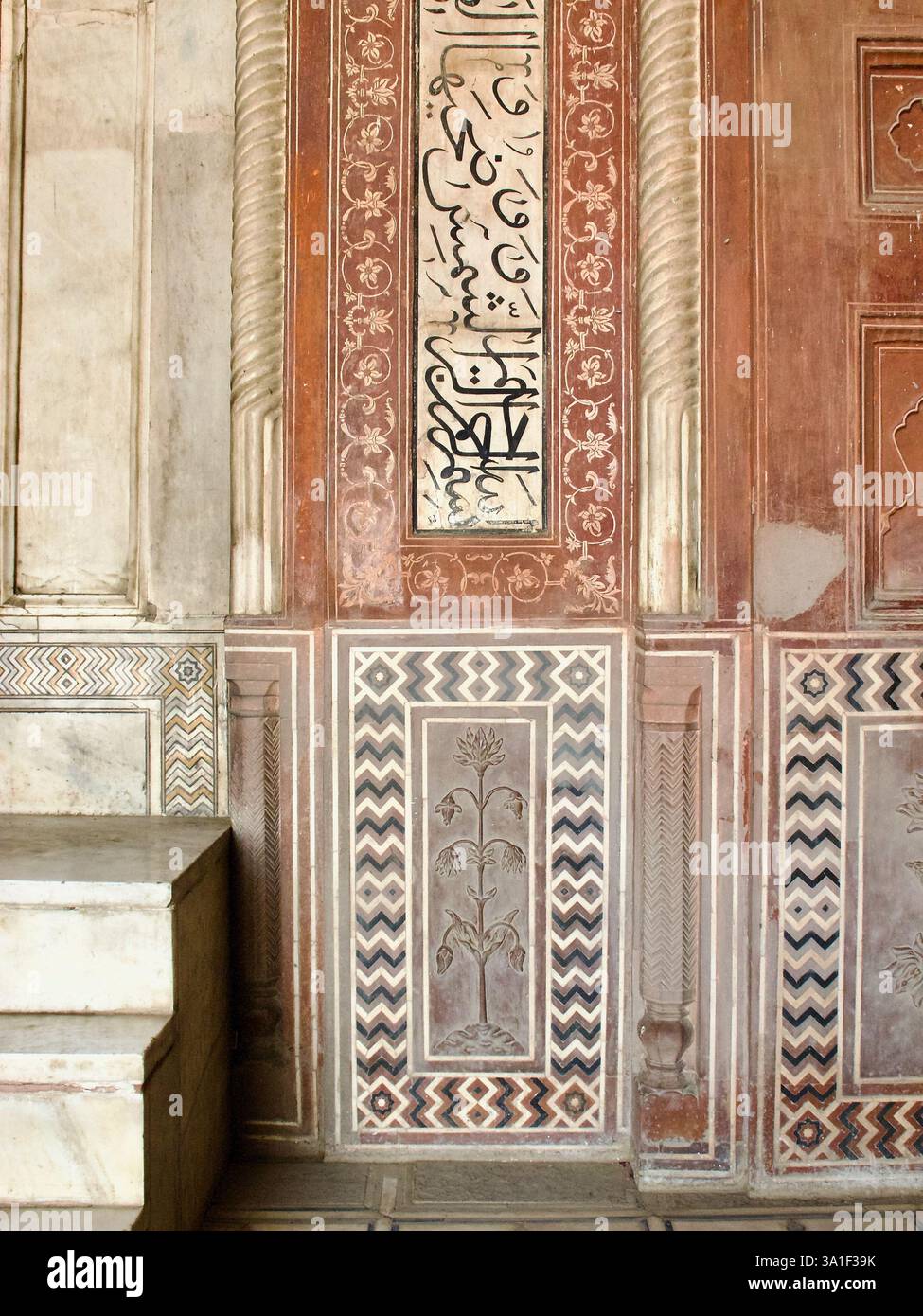 Detail der Korankalligraphie, Blumentafeln und Chevron-Intarsien auf roter Sandsteinwand neben der Minbar in der Taj Mahal Moschee in Agra. Stockfoto
