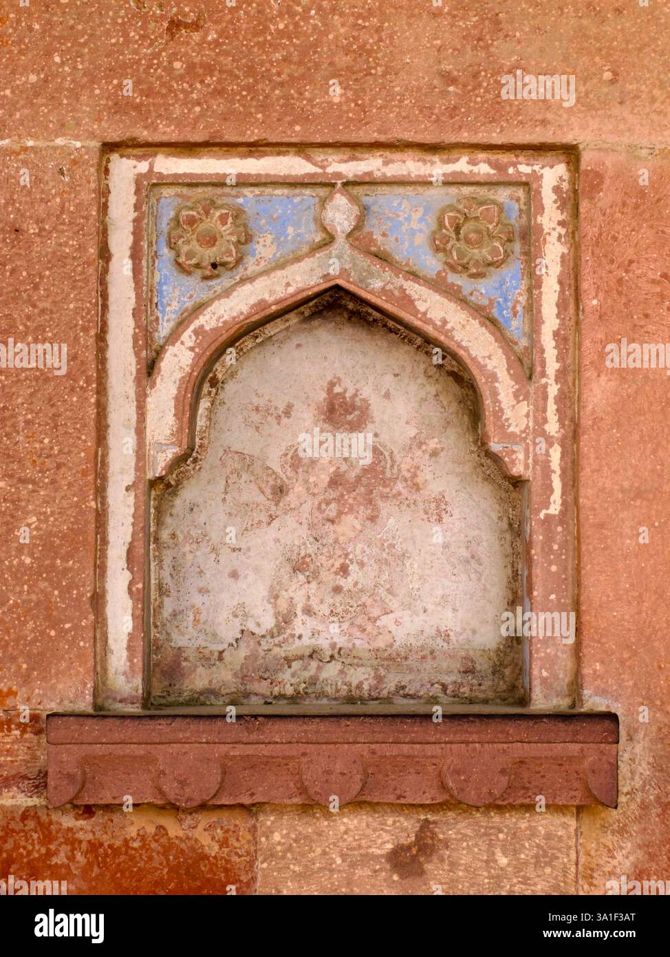 Verblasstes Blumen- und Bogenmotiv an einer verwitterten Wand im Fatehpur Sikri Komplex, Uttar Pradesh, Indien. Stockfoto