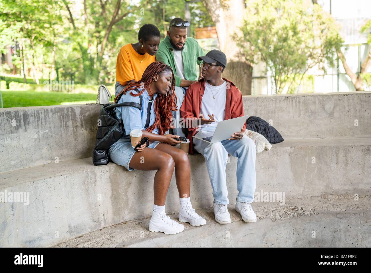 Fokussierte afroamerikanische Studenten Freunde auf der Parkbank, die mit dem Laptop beschäftigt sind. Arbeiten an der Zuweisung Stockfoto