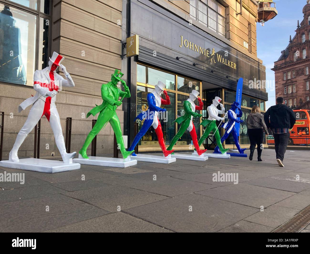 Johnnie Walker Whisky Striding man Statuen in Six Nations Rugby Farben außerhalb der Johnnie Walker Experience, Hope Street, Edinburgh Schottland, 2025 Stockfoto