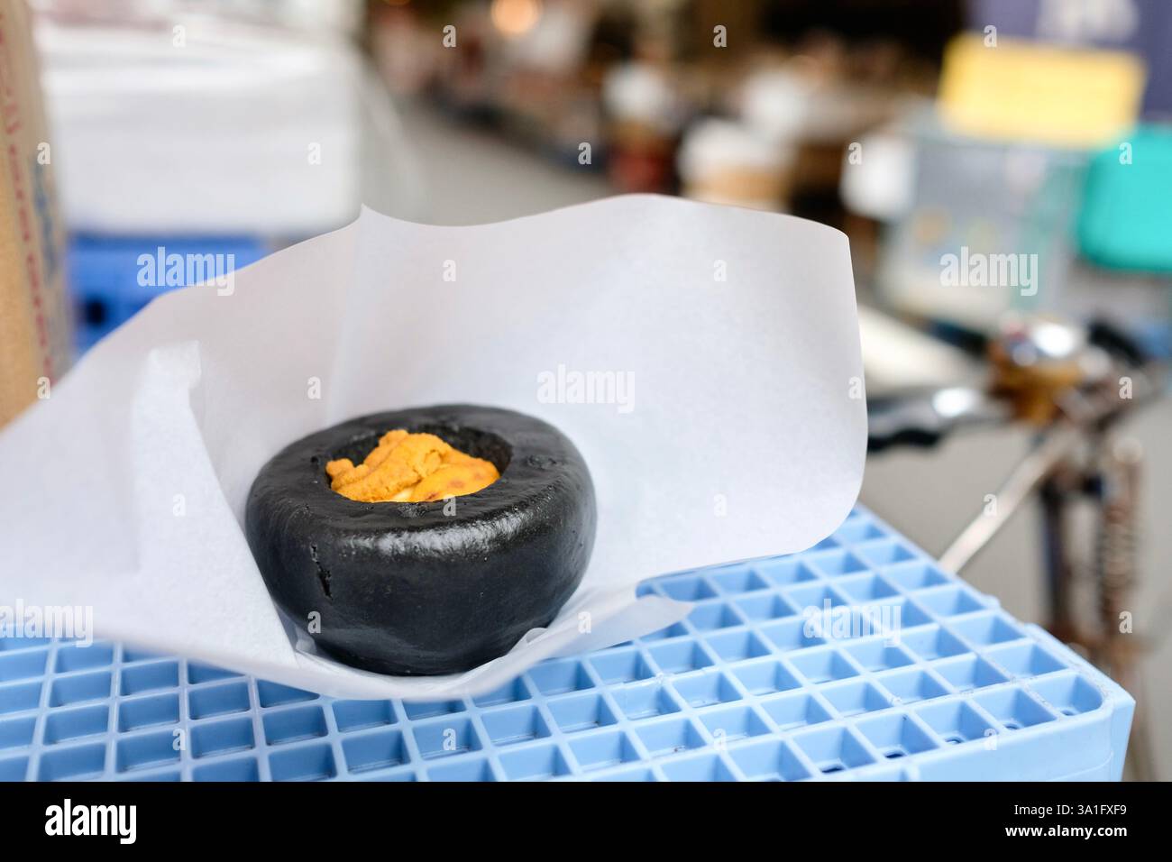 Gedämpftes Seeigel-Brötchen von Hamada Shoten, auf einer blauen Plastikkiste auf dem Tsukiji Outer Fish Market in Chuo, Tokio, Japan Stockfoto