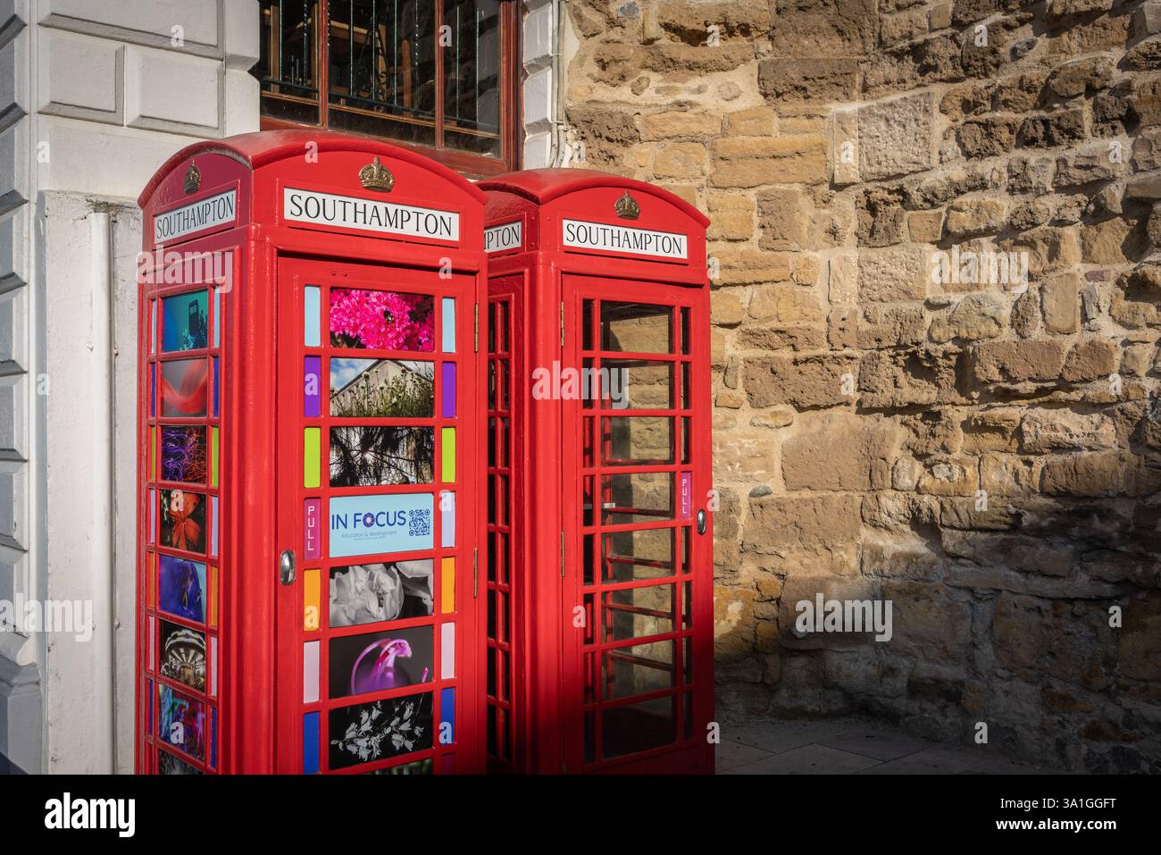 Zwei ikonische britische rote K6-Telefondosen an der Southampton High Street mit den Mauern der Altstadt im Hintergrund. Southampton, England, Großbritannien Stockfoto