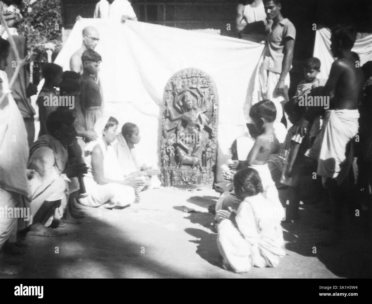 Ein Gottheitsstein, umgeben von Menschen, die ihn betrachten, in Noakhali Ostbengalen, 1946 KEIN MR Stockfoto