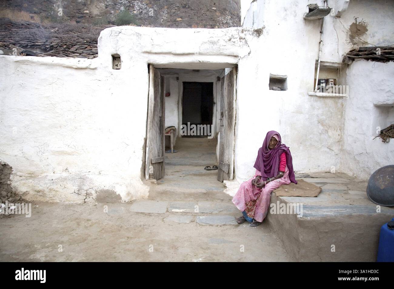 Alte Dame, die vor dem Lehmhaus wartet, Dorf Dilwara, Udaipur, Rajasthan, Indien, Asien Stockfoto