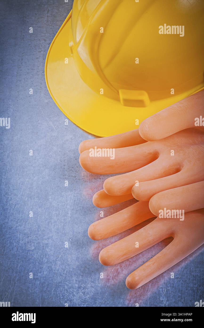 Isolierende Gummihandschuhe, die einen Helm auf metallischem Hintergrund bauen Stockfoto