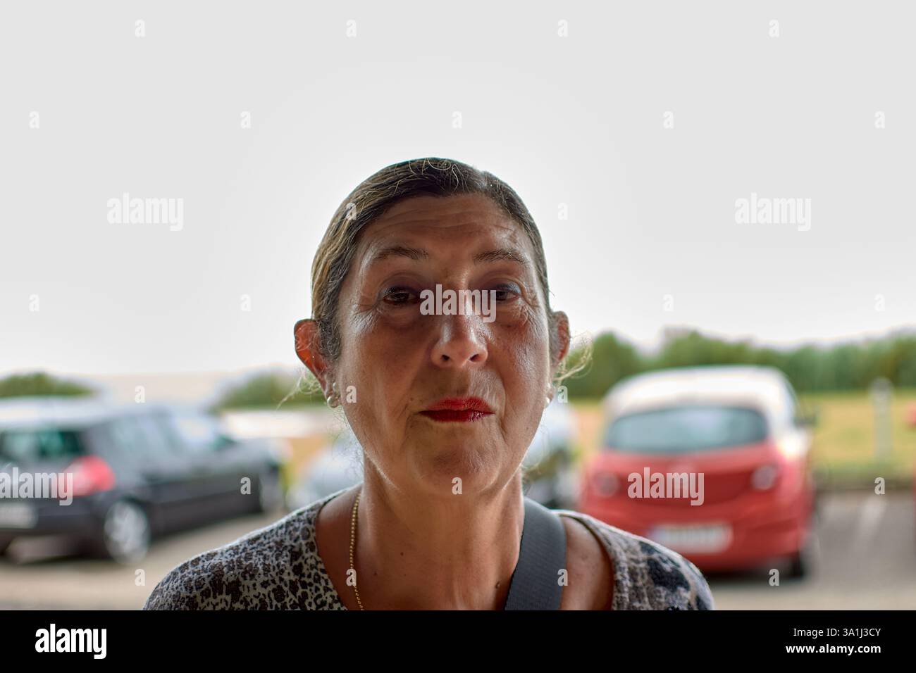 Eine Nahaufnahme einer pensionierten Frau mit ihren Haaren, die an einem bewölkten Tag draußen läuft. Ihr heiterer Ausdruck und das bewölkte Wetter sorgen für eine gute Stimmung Stockfoto