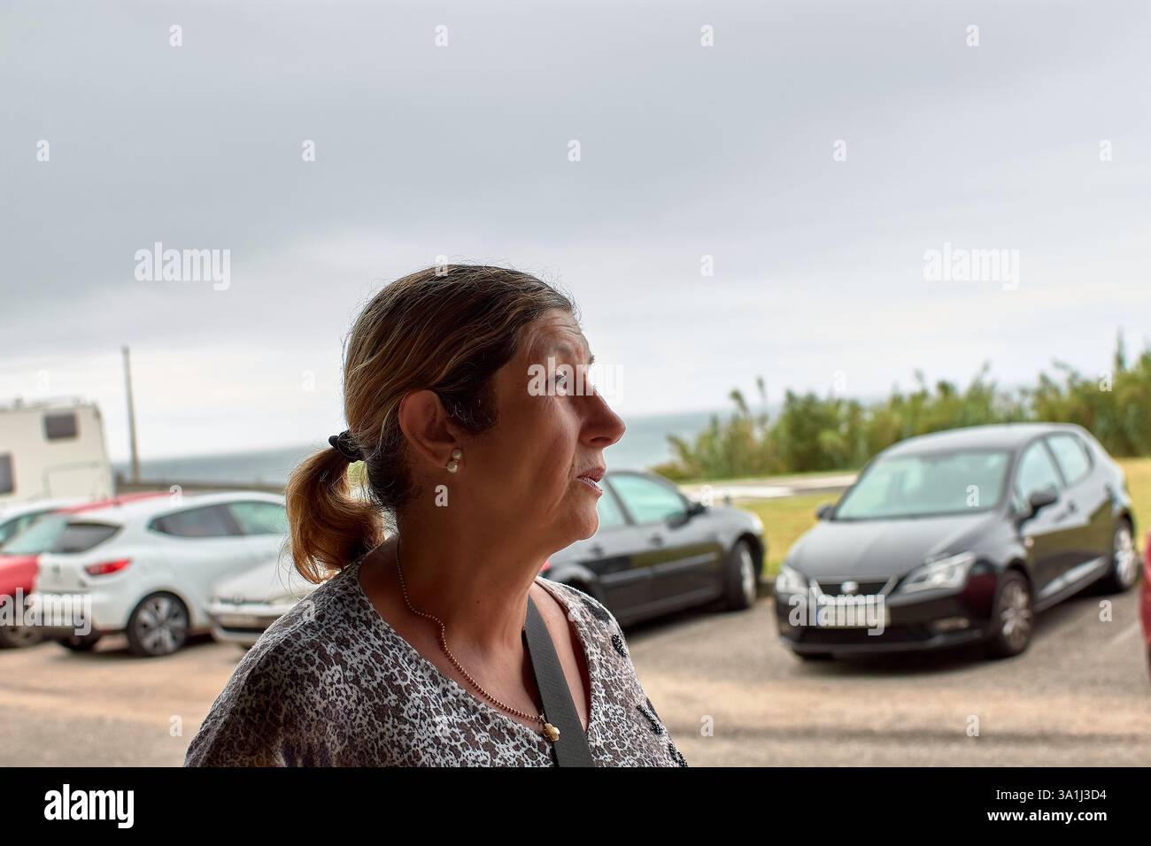 Eine Nahaufnahme einer pensionierten Frau mit ihren Haaren, die an einem bewölkten Tag draußen läuft. Ihr heiterer Ausdruck und das bewölkte Wetter sorgen für eine gute Stimmung Stockfoto