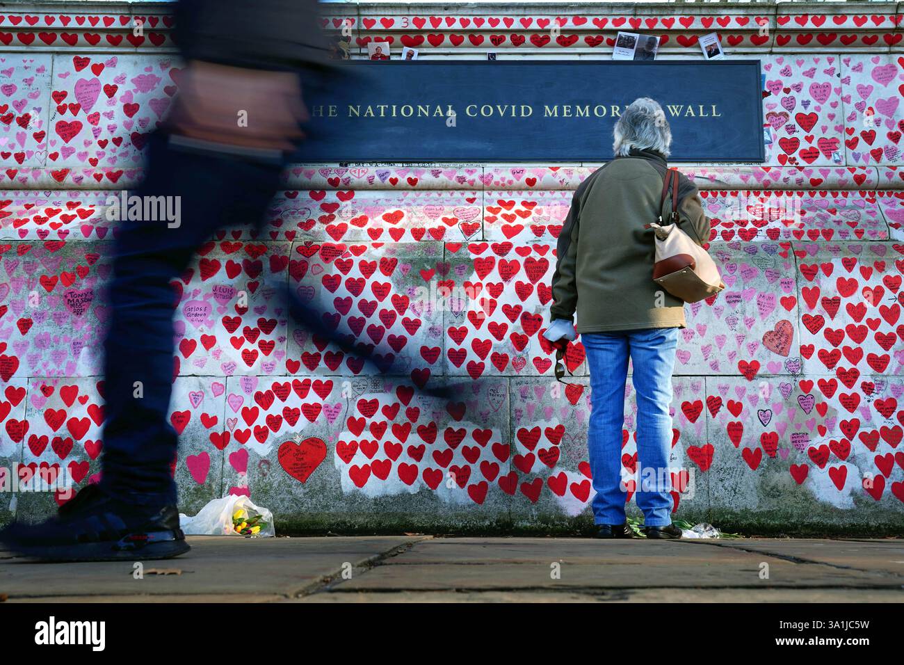 Aktenfoto vom 01/22 einer Frau, die pausiert, um sich Widmungen anzusehen, die an der National COVID Memorial Wall in Westminster, London, geschrieben wurden. Die Erfahrungen der Menschen mit schlechter Gesundheit und Einsamkeit haben sich fünf Jahre nach dem ersten COVID-19-Lockdown nicht verbessert, deuten die Zahlen an, dass die „dauerhaften“ Auswirkungen der Pandemie „viele Menschen isoliert“ lassen. Ausgabedatum: Sonntag, 9. März 2025. Stockfoto