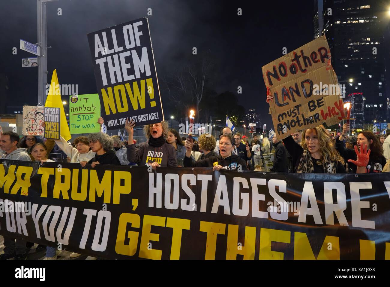 TEL AVIV, ISRAEL - 8. MÄRZ: Ein Demonstrant hält ein Schild mit der Aufschrift „kein anderes Land muss ein anderer Weg sein“ (in Bezug auf den Oscar-ausgezeichneten israelisch-palästinensischen Dokumentarfilm), während Demonstranten während eines Massenprotests den Weg zu einem der Tore des Hauptquartiers des Verteidigungsministeriums blockieren, in dem sie den Abschluss des Waffenstillstandsabkommens mit der Hamas forderten und die Freilassung der verbleibenden Geiseln forderten, die am 8. März 2025 im Gazastreifen in Tel Aviv, Israel festgehalten wurden. Stockfoto