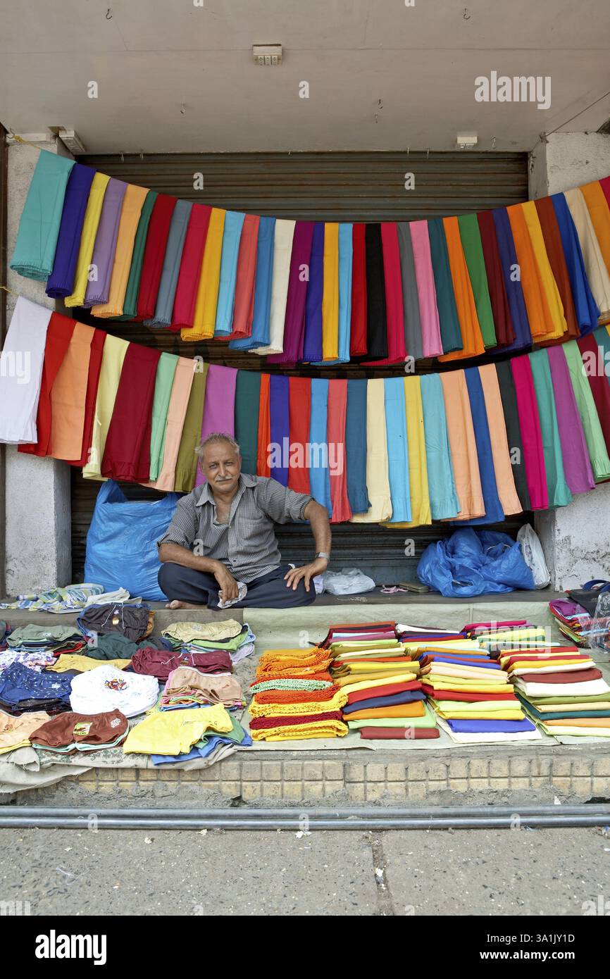 Eine bunte Ausstellung von Kleidungsstücken am Straßenrand, verteilt von einem Händler vor einem geschlossenen Geschäft, Mumbai Bombay, Maharashtra, Indien, Asien Stockfoto