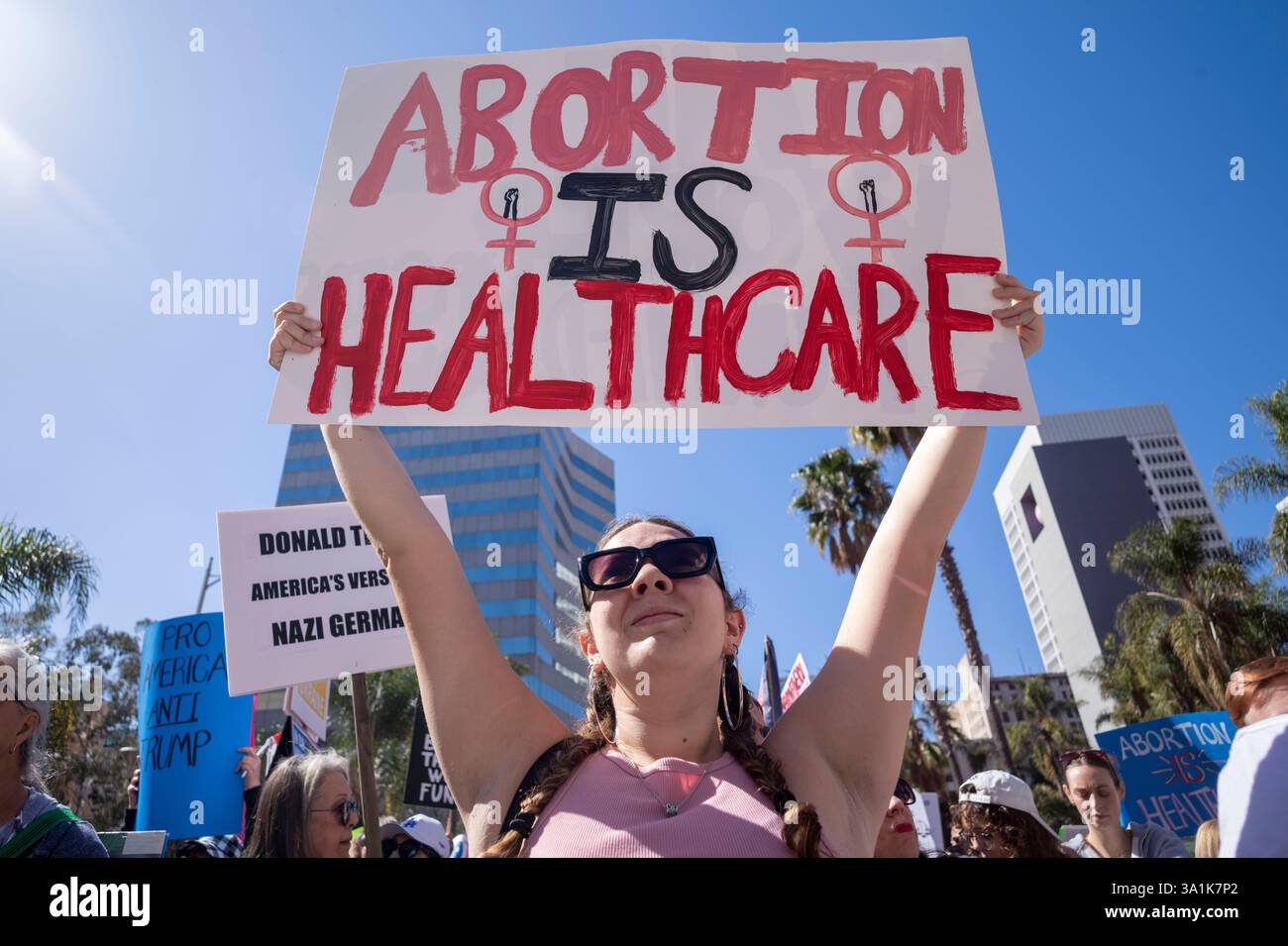 Los Angeles, Usa. März 2025. Eine Demonstrantin hält ein Plakat, als sie zum Frauenmarsch in Los Angeles auf die Straßen der Innenstadt von Los Angeles geht. Quelle: SOPA Images Limited/Alamy Live News Stockfoto