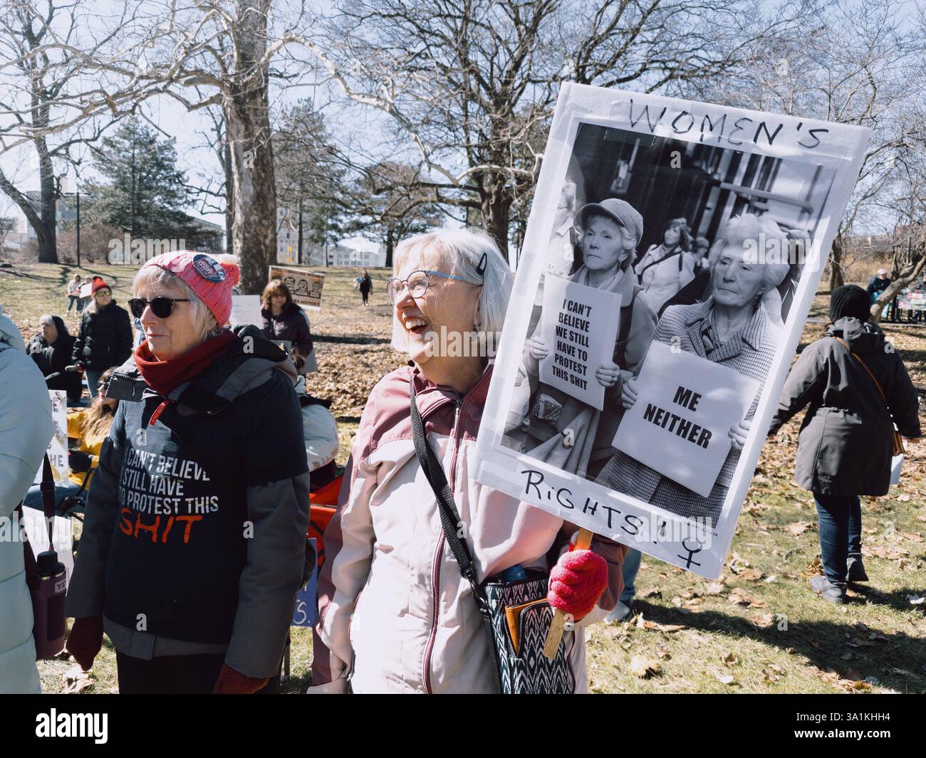 Ältere Frau mit humorvollem Suffragette-Zeichen „Women's [Rights] — ME NONDER!“ Bei der Rallye zum Internationalen Frauentag in Flint Michigan Stockfoto