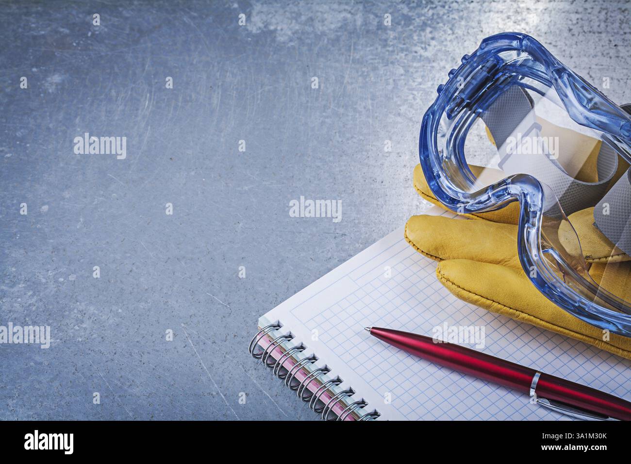 Kunststoffbrille Lederhandschuhe Copybook Stift auf metallischem Hintergrund Stockfoto