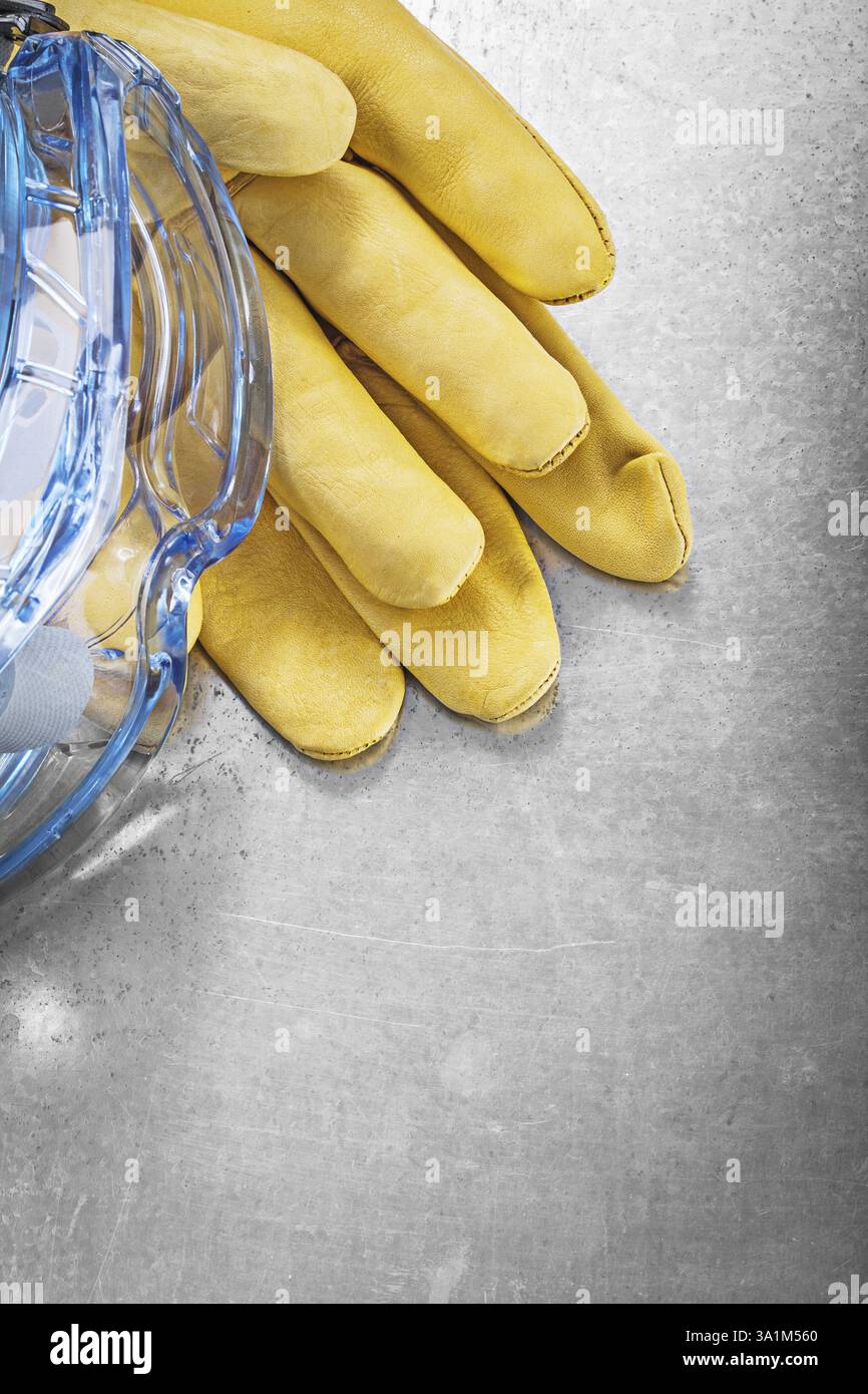 Schutzbrille Lederhandschuhe auf zerkratztem metallischem Hintergrund Konstruktionskonzept Stockfoto