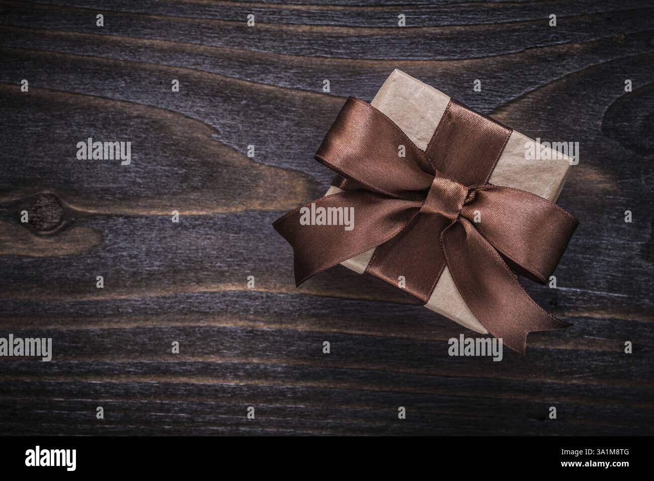 Geschenkbox mit braunem Band auf Vintage-Holzbrett Stockfoto