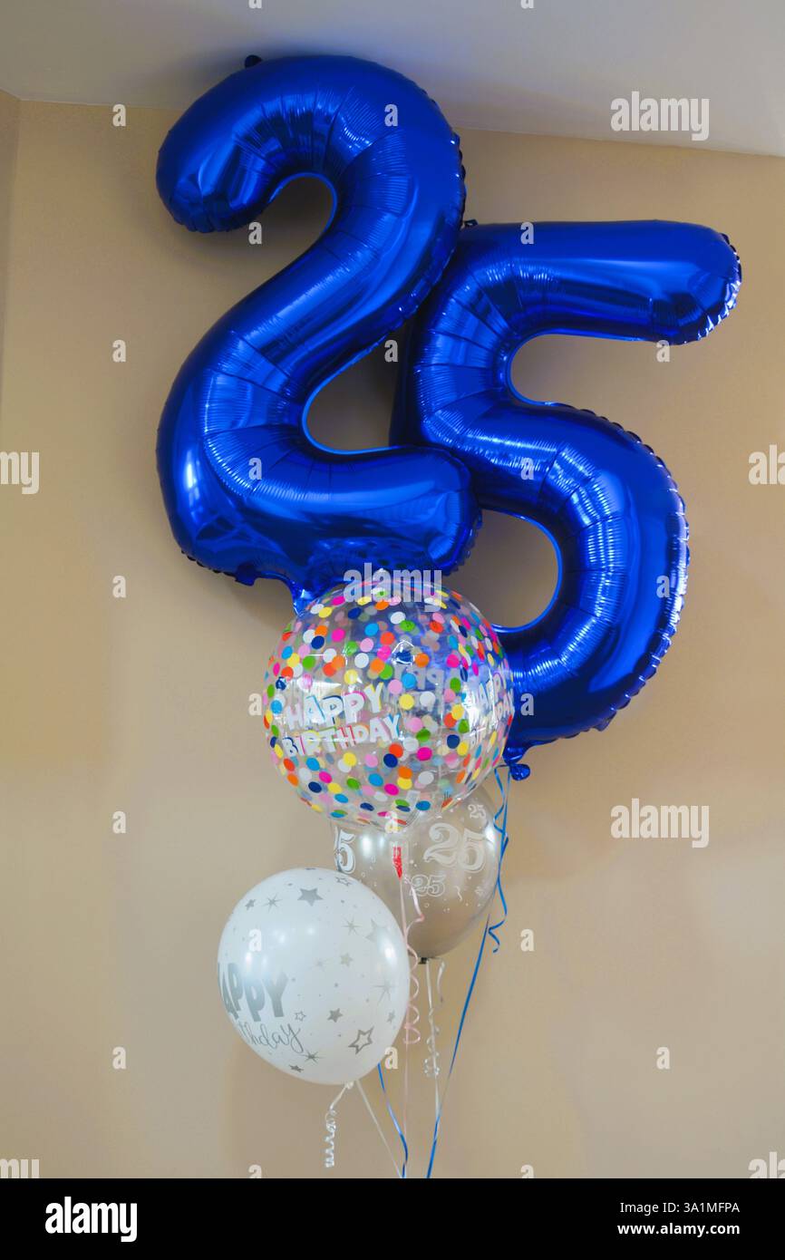 Eine Gruppe blauer und silberner Heliumballons an einer beigefarbenen Wand, die den 25. Geburtstag feiert. Stockfoto
