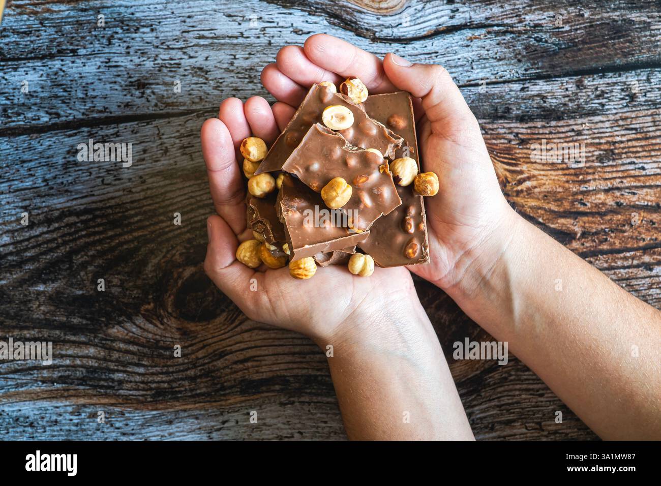 Nahaufnahme der Hände, die mehrere Schokoladentafeln halten. Warmes und appetitliches Bild. Konzepte von Süßigkeiten, Genuss und Gourmetgerichten. Stockfoto