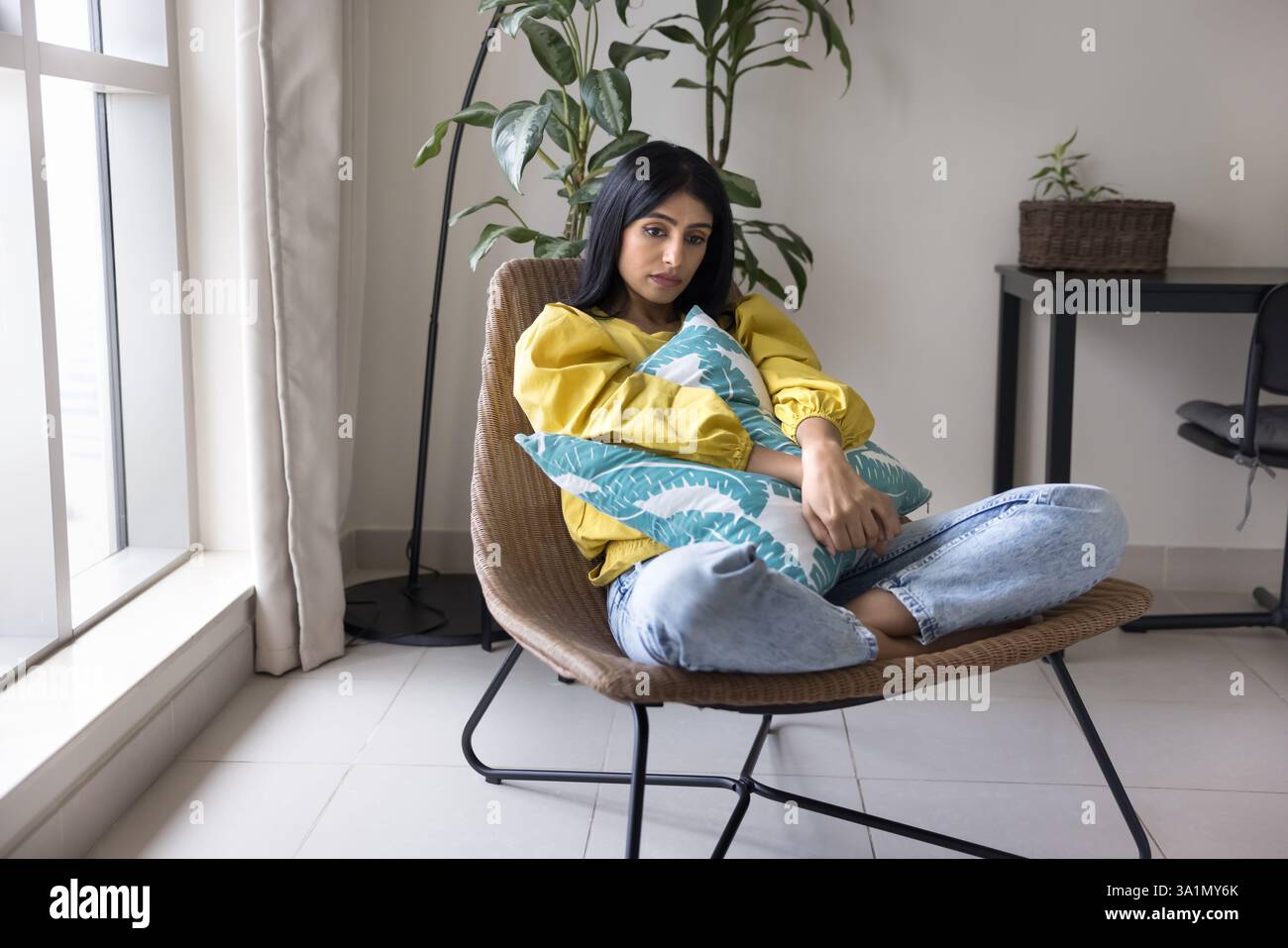 Die indische Frau sitzt im Sessel und sieht melancholisch, verärgert und unglücklich aus Stockfoto