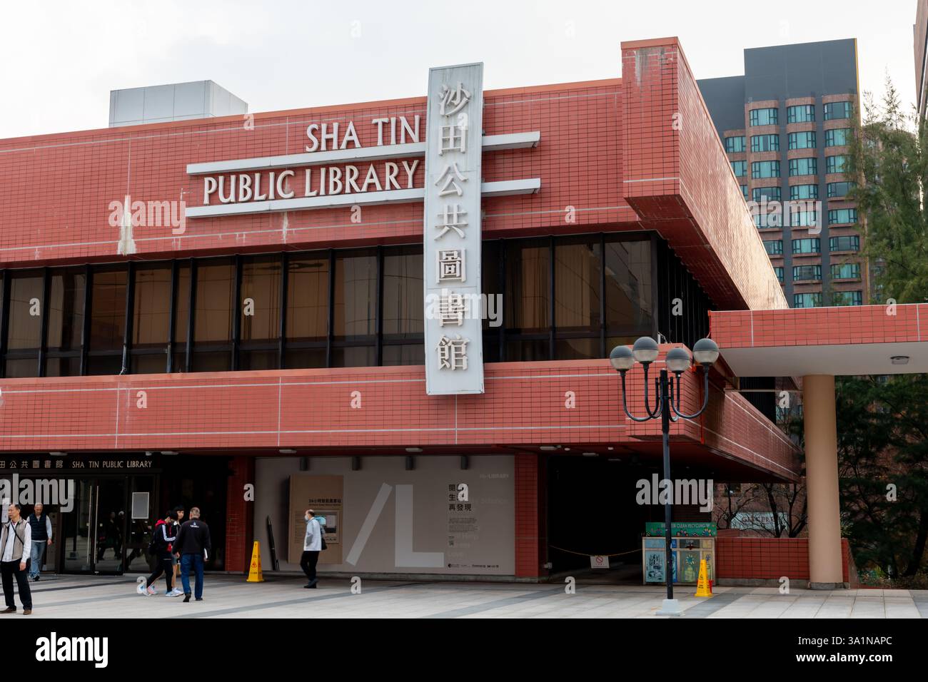Hongkong. China- 02.16.2025. Außenansicht der Sha Tin Library mit der Fassade des Gebäudes und Namensschild auf Chinesisch und Englisch mit Fußgängern Stockfoto