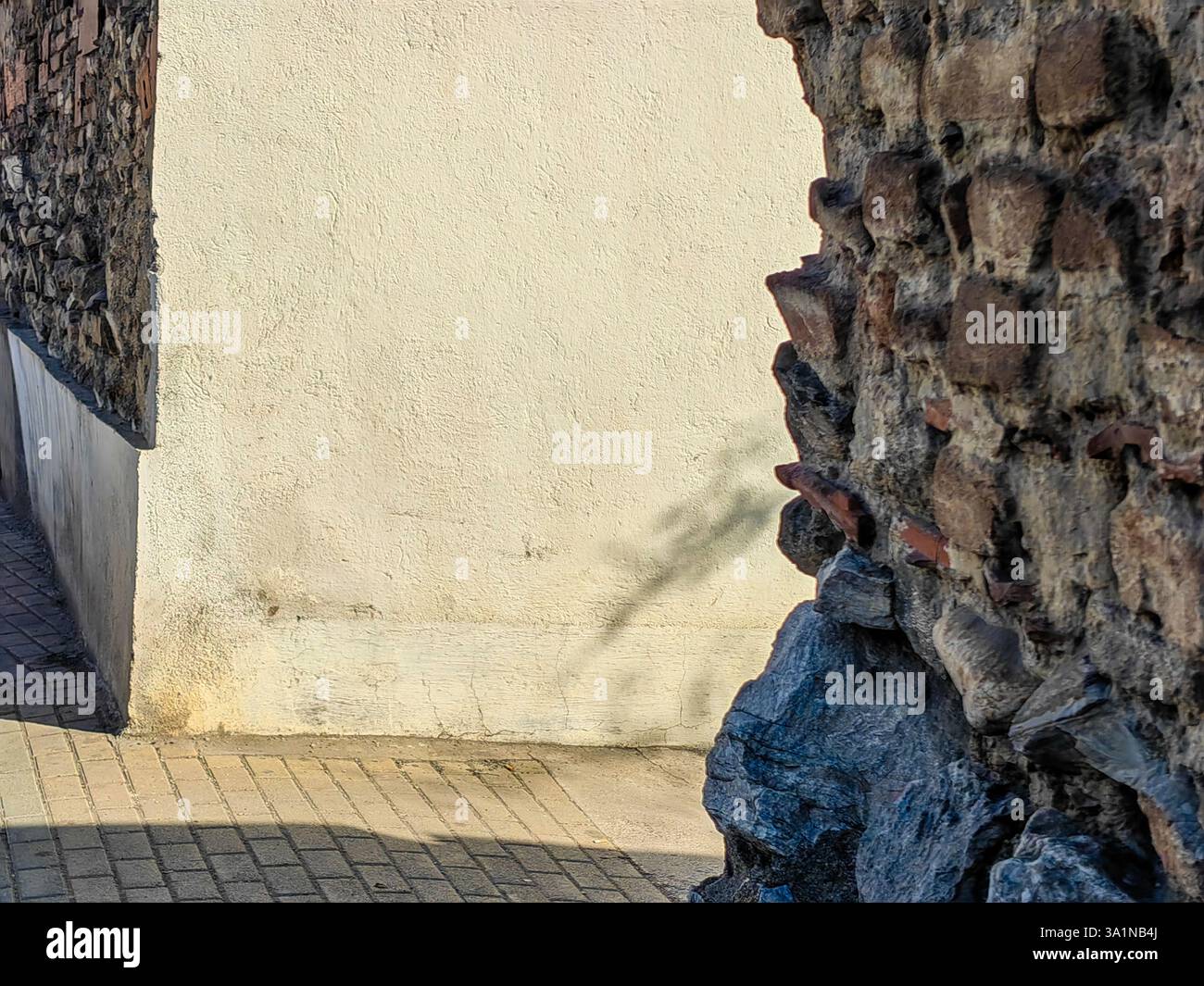 Sonnendurchflutete Schatten – unscharfe Steinmauer in der Morning Alley Stockfoto