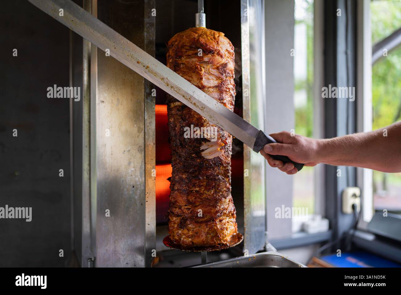 Der Koch bereitet traditionelles türkisches Dönerfleisch zu. Gegrilltes Fleisch für die Herstellung eines traditionellen türkischen Essens Döner Kebab oder griechischer Gyros. Stockfoto