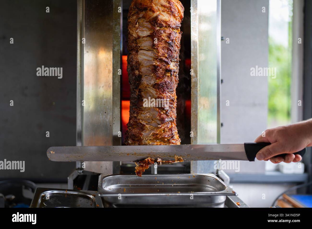 Der Koch bereitet traditionelles türkisches Dönerfleisch zu. Gegrilltes Fleisch für die Herstellung eines traditionellen türkischen Essens Döner Kebab oder griechischer Gyros. Stockfoto