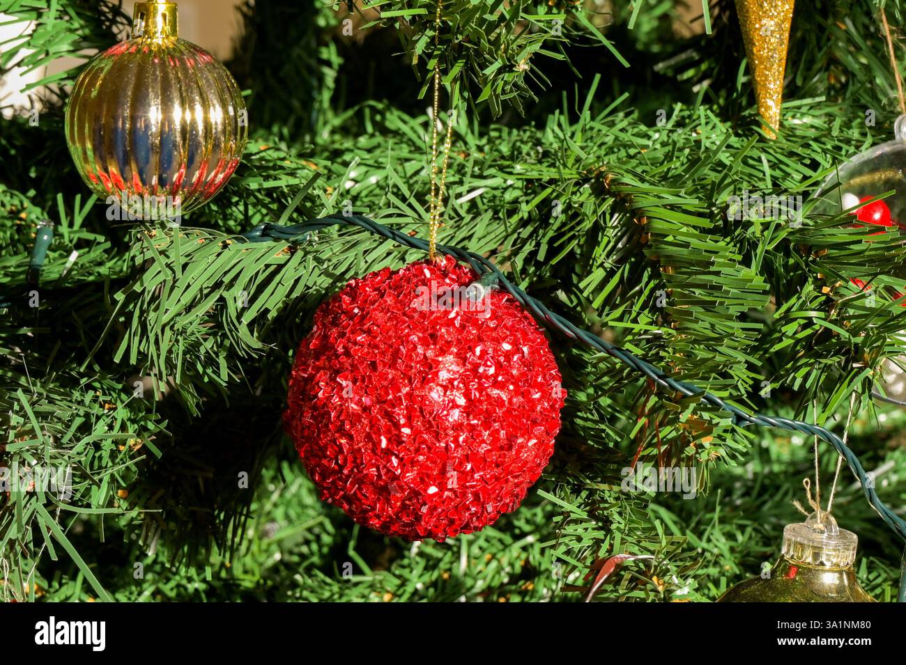 Weihnachtsbaum mit einer großen roten Kugel und anderen Dekorationen. Keine Personen. Stockfoto