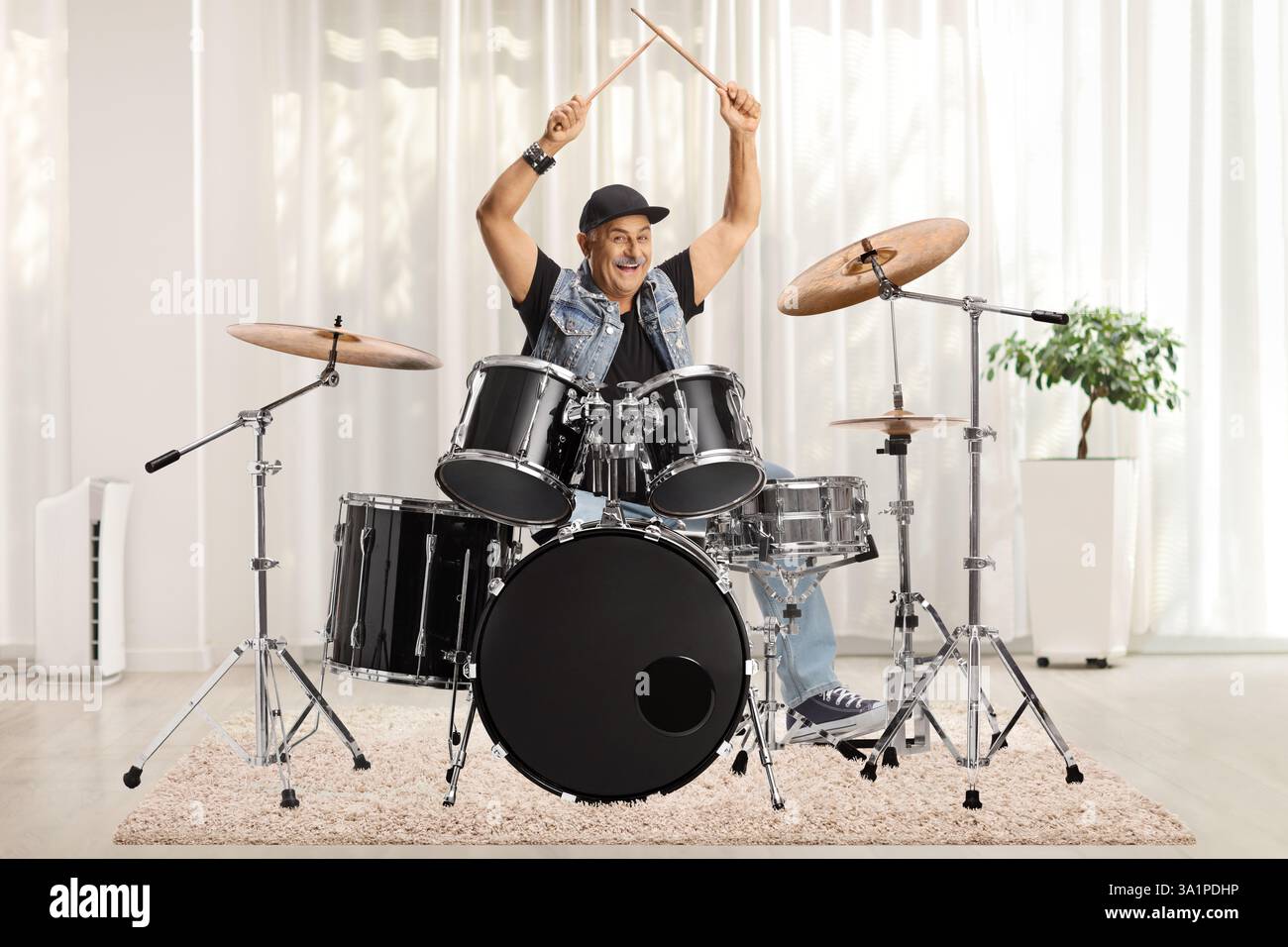 Ein reifer Schlagzeuger mit Schlagzeugern tritt in einem Raum auf Stockfoto