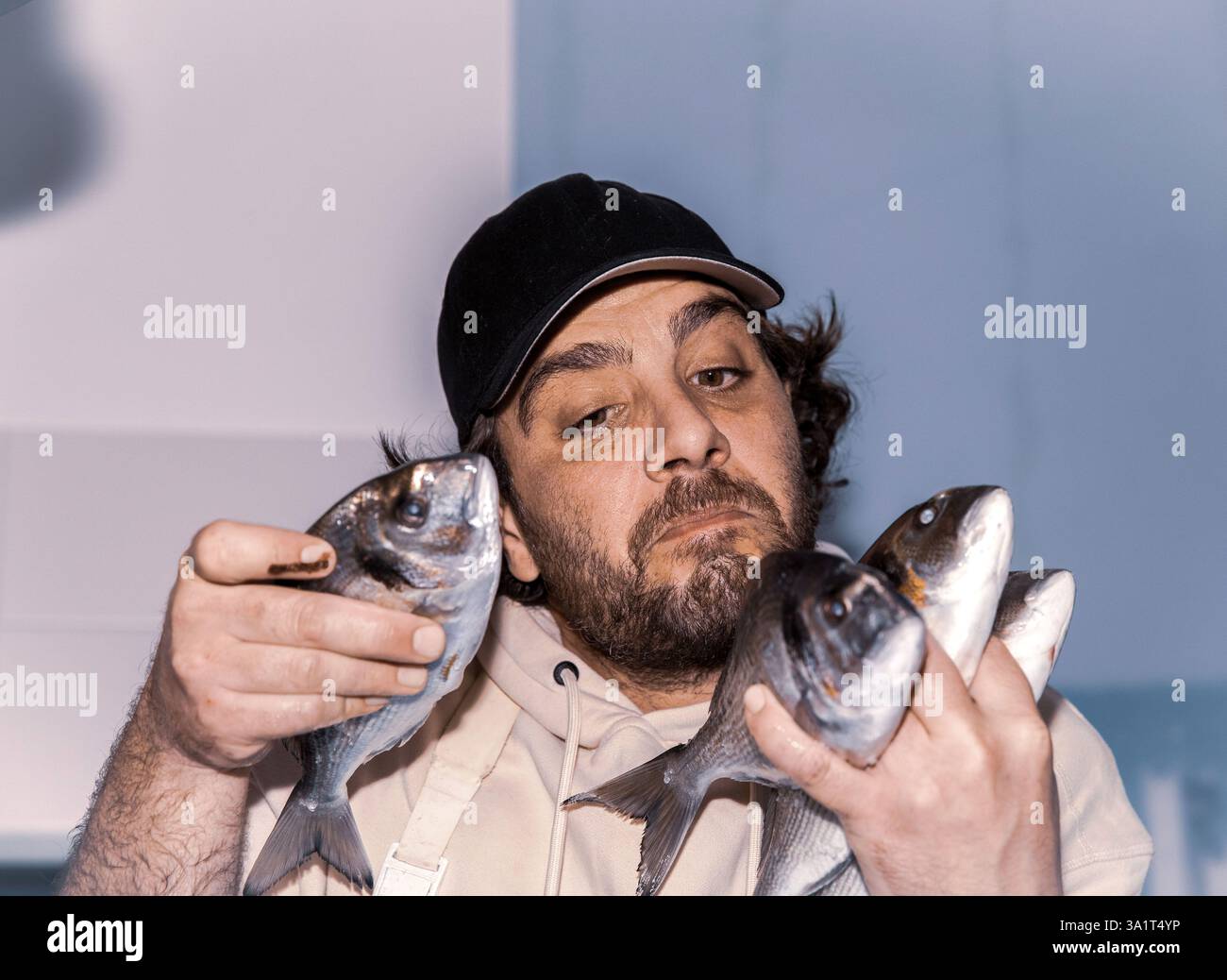 Kaukasischer männlicher Erwachsener, der frischen Fisch mit ernstem Ausdruck hält Stockfoto