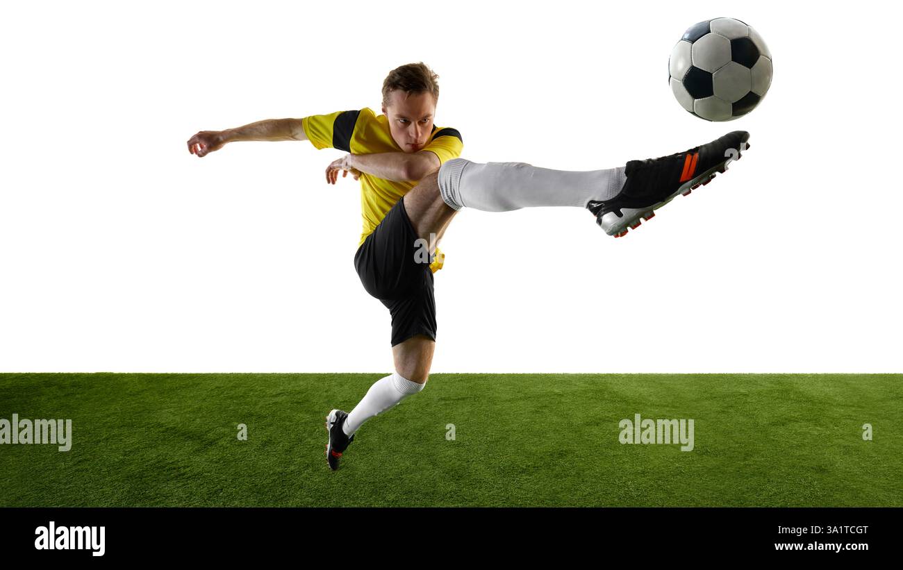 Seitenansicht eines fokussierten jungen Mannes, eines Fußballspielers, der akrobatische Hochtritte durchführt, das Bein in Richtung Ball hebt und intensiv vor weißem Hintergrund fokussiert. Stockfoto