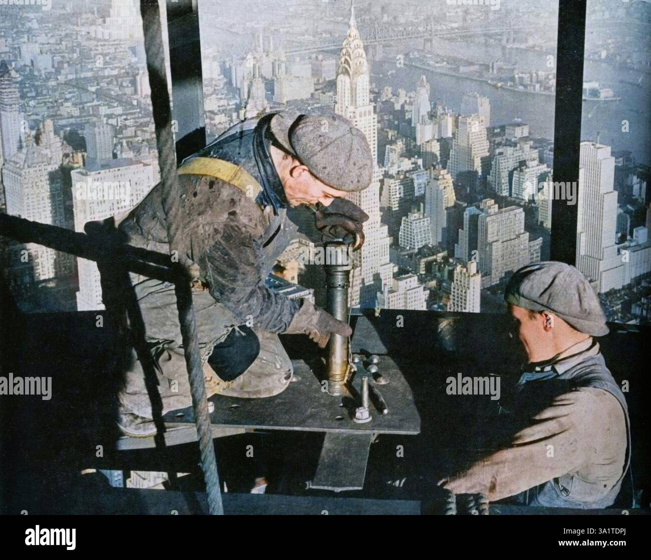 "Nieten der letzten Bolzen am "Morgenmast" des Empire State Building", 1931. Nieten der letzten Bolzen am "Morgenmast" des Empire State Building. Die Gebäude Chrysler, News und Grand Central befinden sich unter anderem in der Nähe von Blackwell's Island. Das Empire State Building wurde von William F. Lamb vom Architekturbüro Shreve, Lamb and Harmon entworfen. Die Arbeiten begannen am 22. Januar 1930 und das Gebäude wurde am 1. Mai 1931 offiziell eröffnet. Aus „The Studio Volume 103“. [London Offices of the Studio, London, 1932]. Stockfoto