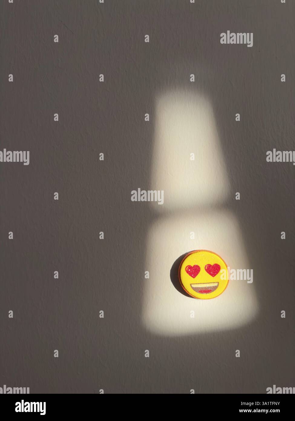 Herzäugiger Emoji-Magnet wirft einen Schatten auf eine schwach beleuchtete Wand, Truthahn Stockfoto