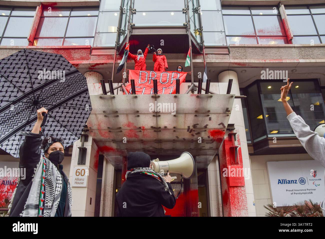 London, Großbritannien. März 2025. Aktivisten der Gruppe Palestine Action klettern auf den Eingang der Allianz-Büros in der City of London, nachdem sie das Gebäude mit roter Farbe besprüht haben. Die Aktivisten rufen den Versicherungsriesen auf, Verbindungen zum Waffenunternehmen Elbit Systems zu unterbrechen. Quelle: Vuk Valcic/Alamy Live News Stockfoto