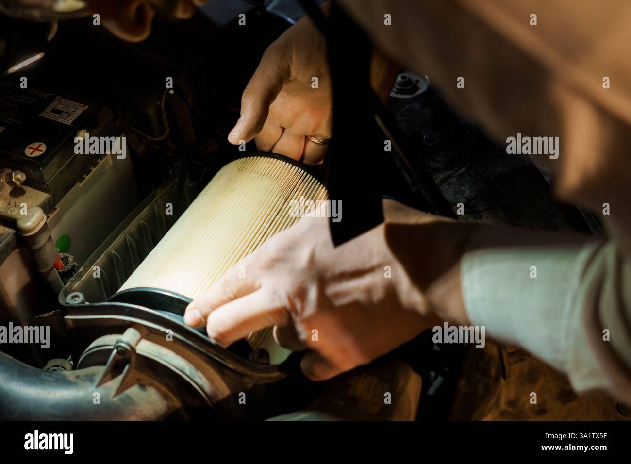 Nahaufnahme der Hände, die den Luftfilter unter der Motorhaube im Kfz-Wartungsverfahren ersetzen. Stockfoto