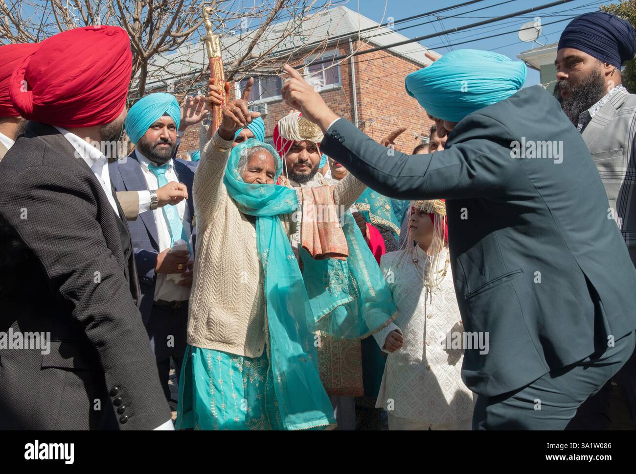 Mit dem Bräutigam im Hintergrund feiern Sikhs die bevorstehende Hochzeit mit Lachen und Tanzen. In New York City. Stockfoto